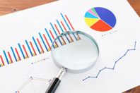 GettyImages-1889687267-graphs-maginfying-glass-charts-white-paper