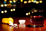 spilled pills with glass of rum whiskey-GettyImages-168413779