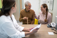 Senior man with daughter at doctors office-GettyImages-1837504525