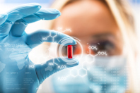 Applications Of Liquid-Filled Capsules In Pharmaceutical Manufacturing Scientist holding pill-GettyImages-849469292
