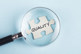 GettyImages-1493832785-magnifying-glass-quality-blue-background-puzzle-piece