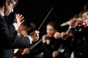 Conductor directing symphony orchestra-GettyImages-490338206
