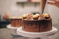 Confectioner decorating chocolate cake-GettyImages-1187830875