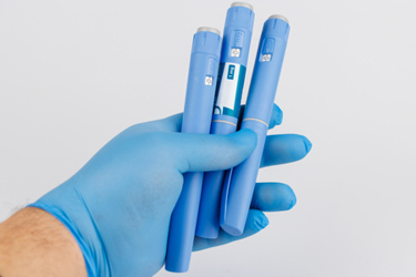 GettyImages-2212761340-gloved-hand-GLP-1-injector