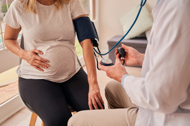 doctor testing blood pressure of pregnant Caucasian female-GettyImages-1358703345
