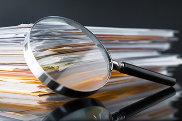 Magnifying glass files regulatory documents GettyImages-614037306