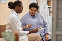 Building Trust: Overcoming Barriers To Clinical Trial Diversity Female Patient Listening to Doctor Holding Tablet-GettyImages-1947527002