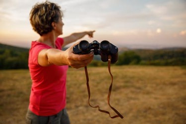woman with binoculars and pointing-GettyImages-1452691834
