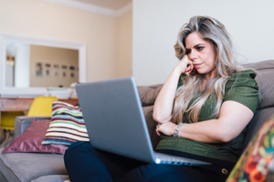 Sad woman using laptop-GettyImages-1324057284