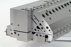 Three manifolds are visible in this view of one end of an Ultracoat(TM) slot die coating head. The manifold cross sections appear as partially teardrop-shaped openings that narrow into thin flow channels. The bottom-most coating layer is horizontal in this picture, and the next two layers are oriented at an angle to it.  After the three layers join, the resulting single structure flows out the exit slot at the die lips, which appear at lower right in the photo.