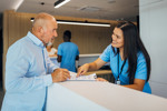 Senior man at clinic reception desk-GettyImages-2174582061