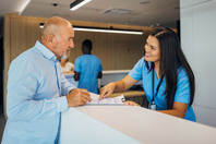 Senior man at clinic reception desk-GettyImages-2174582061