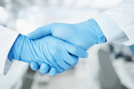 GettyImages-1600718991-gloved-hand-labcoat-scientist-handshake