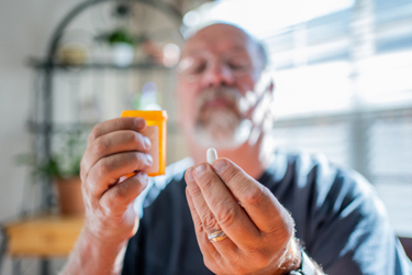 Mature Man Scrutinizing His Perscription Medications-GettyImages-1418052436