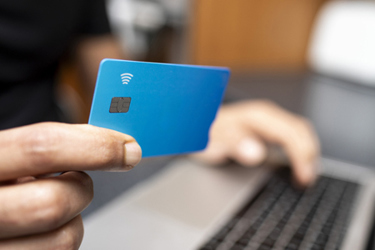 hand holding credit card, laptop-GettyImages-2207149857 hand holding credit card, laptop-GettyImages-2207149857