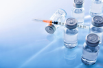 GettyImages-867398442 Vials And Syringe On Blue Table Top
