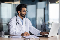 GettyImages-1562983761-doctor-laptop-notebook-pen-table-office