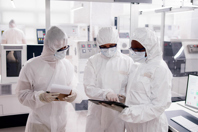 GettyImages-1714483159-group-of-scientists-laboratory-tablet-coveralls