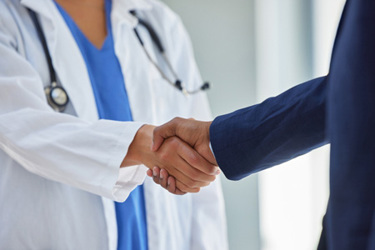 Doctor and businessman shaking hands-GettyImages-1321229984