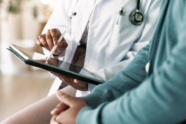 GettyImages-2183708450-doctor-with-patient-tablet-doctors-office