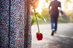 woman holding rose man walking away