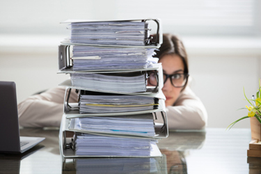 businesswoman hiding behind stack folders-GettyImages-915451280