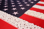 U.S. Tariffs And Their Tenuous Impact On Clinical Trials Various Pills on White Stripes of American Flag-GettyImages-172849908