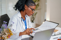 Black female doctor reviews medical record-GettyImages-2231130594