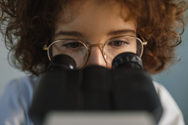 Medical researcher looking through a microscope-GettyImages-1310989321