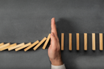 GettyImages-1126856471 stopping dominoes falling