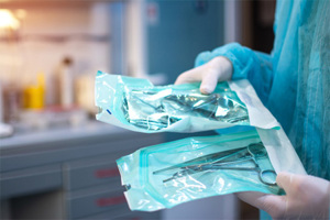 GettyImages-1338518556-gloved-hands-sterile-packaging-surgical-equipment