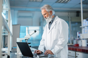 GettyImages-1453524887-scientist-in-lab-with-computer-and-microscope