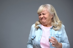 Old woman holding beverage and wrinkling with disgust.jpg