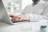 Doctor with laptop clinical data iStock-1191691943